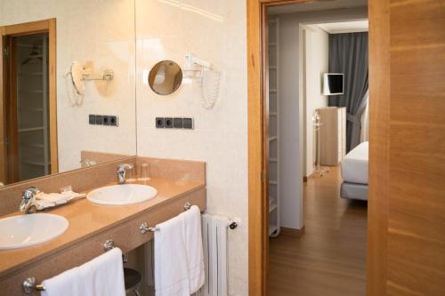 a bathroom with two sinks and a mirror at Hotel Sercotel Tres Luces in Vigo