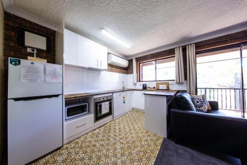 a kitchen with white appliances and a couch in a room at Leski Club in Jindabyne