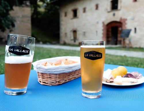 zwei Gläser Bier und ein Teller Essen auf dem Tisch. in der Unterkunft Forte di Machaby in Arnad