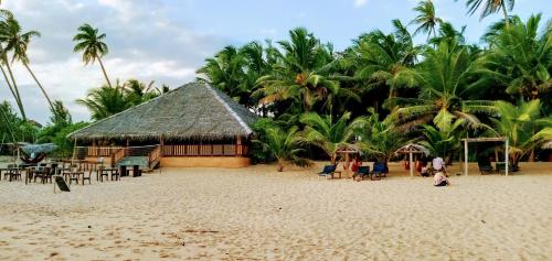 a resort on a beach with palm trees at Ganesh Garden Beach Cabanas in Tangalle