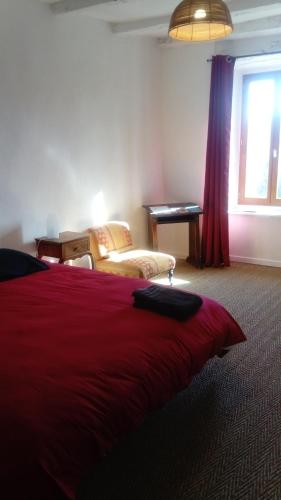 1 dormitorio con cama roja, ventana y escritorio en B and B Sycomore, La Bouriotte, en Labastide-Rouairoux