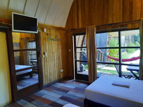 a room with a bed and a tv and a window at M'adison Gilli in Gili Trawangan