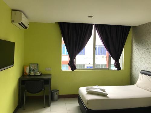 a bedroom with a bed and a window and a desk at SARIKEI GARDEN HOTEL in Sarikei