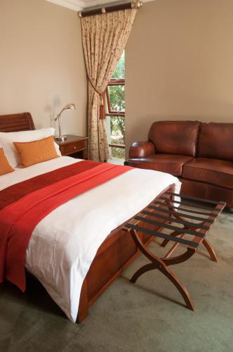 a bedroom with a bed and a leather couch at Village Ridge Boutique Stays in Pretoria