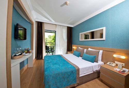 Cette chambre d'hôtel dispose d'un lit avec un mur bleu. dans l'établissement Limak Limra Hotel & Resort Kemer - Kids Concept, à Kemer