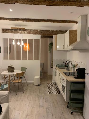 une cuisine avec des armoires blanches et une table avec des chaises dans l'établissement Magnifique nid douillet au coeur du Panier SooHome, à Marseille