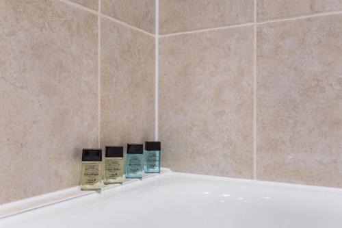 three bottles ofodorizers sit on the edge of a bath tub at All2Stay South Kensington Apartment in London