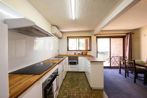 a kitchen with white appliances and a dining room with a table at Leski Club in Jindabyne