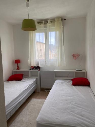ein Schlafzimmer mit zwei Betten und einem Fenster mit Badewanne in der Unterkunft Vallon 3 pièces avec balcon in Trouville-sur-Mer