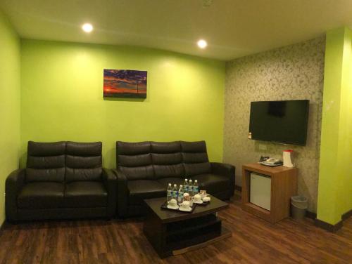a living room with a couch and a flat screen tv at SARIKEI GARDEN HOTEL in Sarikei