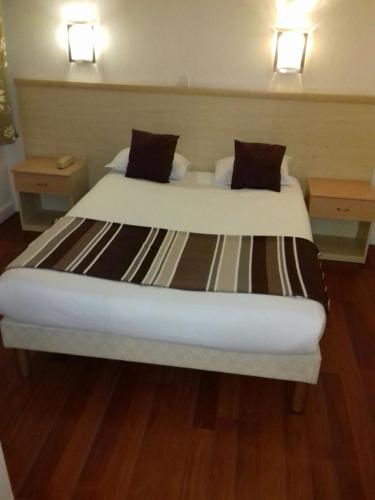 a large bed in a room with two night stands at Hôtel Du Midi in Narbonne