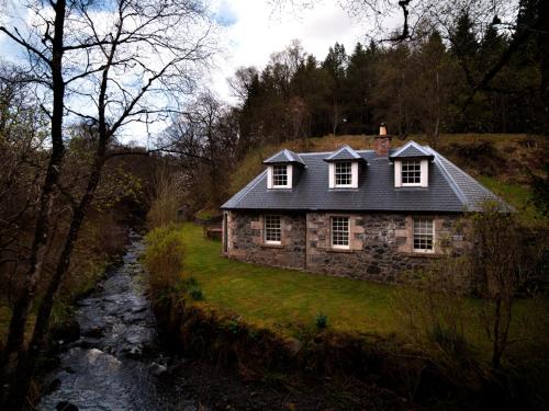 una vieja casa de piedra a orillas de un río en Find Me Out Holiday Cottage, en Dalmellington
