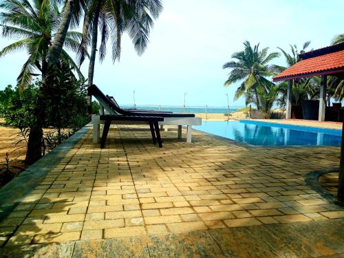 a bench sitting on a patio next to a swimming pool at Wellé Wadiya Beach Villa in Kalpitiya