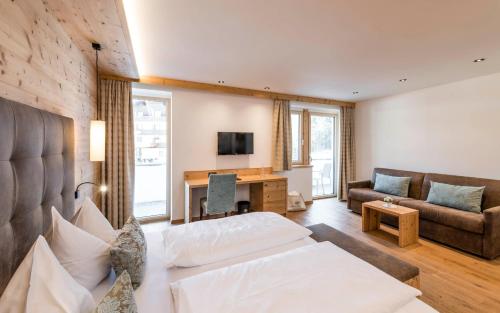 a living room with a bed and a couch and a desk at Hotel Waldsee in Völs am Schlern