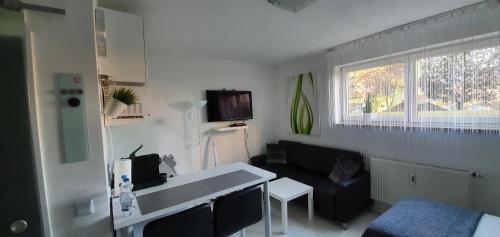 pequeña sala de estar con sofá negro y cocina en Unique Messe - Airport en Steinenbronn