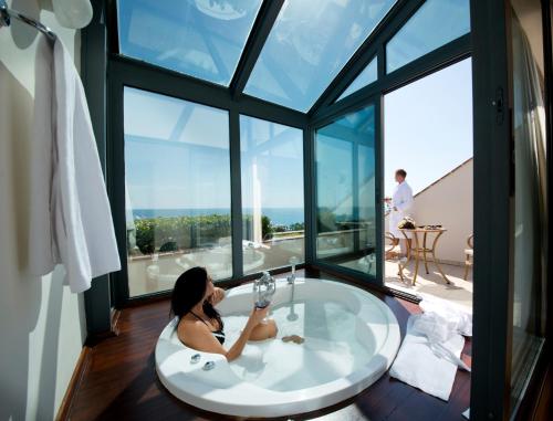 a woman sitting in a bath tub in a room with large windows at Limak Limra Hotel & Resort Kemer - Kids Concept in Kemer
