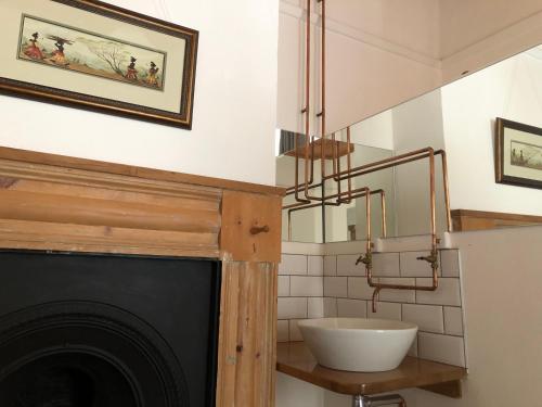 a bathroom with a fireplace with a sink and a mirror at At The Loerie in Knysna
