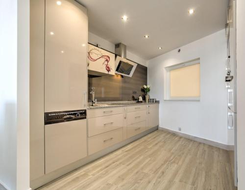 a large kitchen with white cabinets and a window at Vila Gaivota 3G in Ferragudo