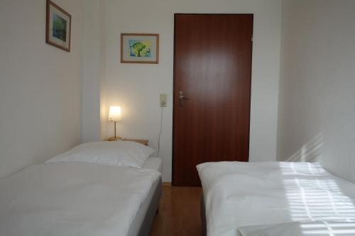 a bedroom with two beds and a door with a lamp at Pension am Helenenwall in Cologne