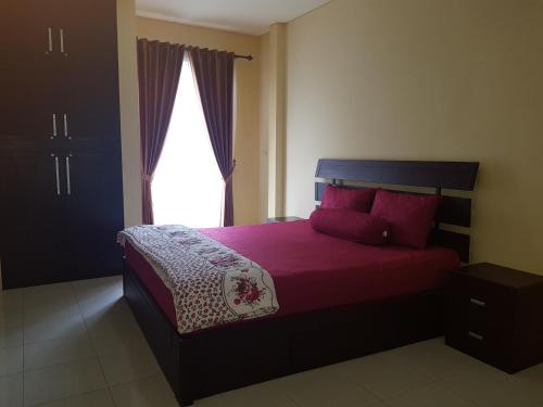 Schlafzimmer mit einem Bett mit roten Kissen und einem Fenster in der Unterkunft Villa Batu Iggy in Batu