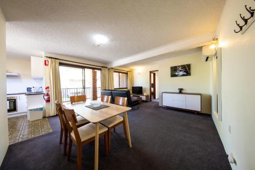 a living room with a table and a kitchen at Leski Club in Jindabyne