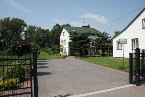 uma entrada que leva a uma casa branca com um portão em Albinos em Albigowa