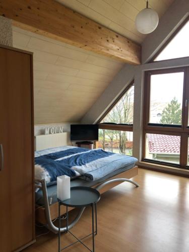 Schlafzimmer mit einem Bett, einem Tisch und Fenstern in der Unterkunft Haus Kleewiese in Ulmen
