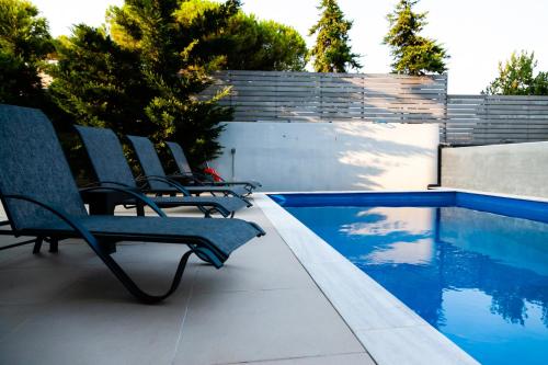 a group of chairs sitting next to a swimming pool at Seaview Pool Villa near Beach and Athens Airport in Porto Rafti