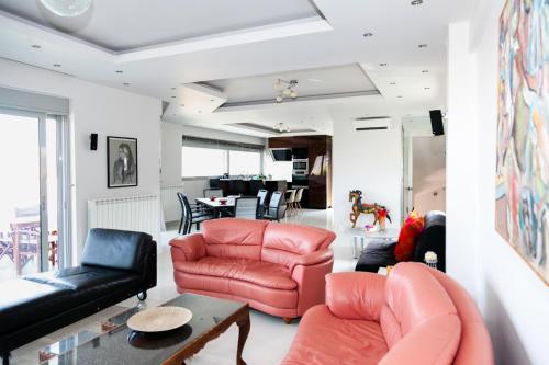 a living room with red leather chairs and a table at Seaview Pool Villa near Beach and Athens Airport in Porto Rafti