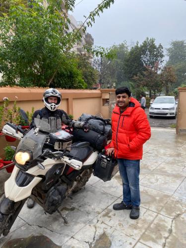 a man is standing next to a motorcycle at Backpackers Den in Lucknow