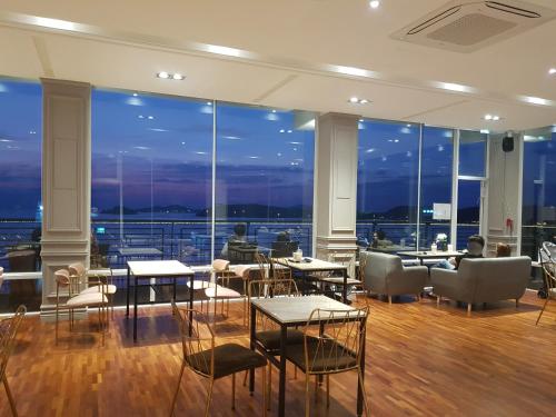 a restaurant with tables and chairs and large windows at Hotel Hue Loft in Incheon