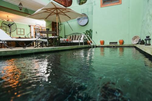 a swimming pool with an umbrella and some chairs at Casa Colonial Koenig in São Filipe