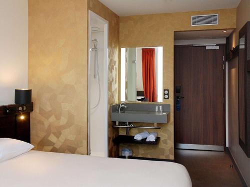 a bathroom with a bed and a sink in a room at Ibis Budget Annecy sud-Poisy in Poisy