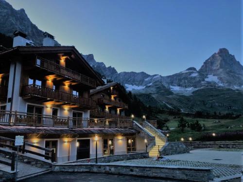 a building with a staircase in front of a mountain at 3 Chalets Aparthotel in Breuil-Cervinia