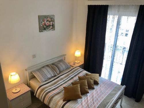 una camera da letto con un letto con cuscini e una finestra di Lighthouse Beach apartment a Paphos