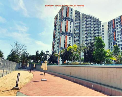 a sidewalk with an umbrella and a tall building at Timurbay Seafront Residence Apartment 2 Room with garden view by imbnb in Kampung Sungai Karang