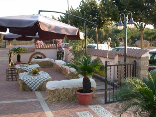 a patio with couches and tables and an umbrella at Agriturismo Torre Cristina in Aprilia