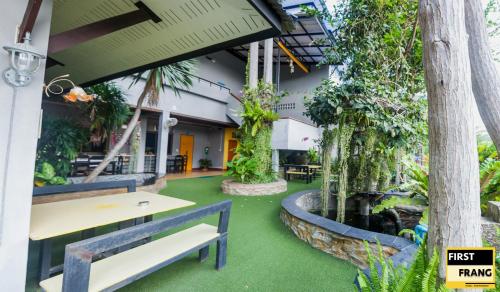 a patio with a table and benches and plants at First and Frang Hotel - Koh Phangan in Thongsala