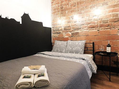 - une chambre avec un lit, des serviettes et un mur en briques dans l'établissement Apartament BAJ No.2, à Toruń