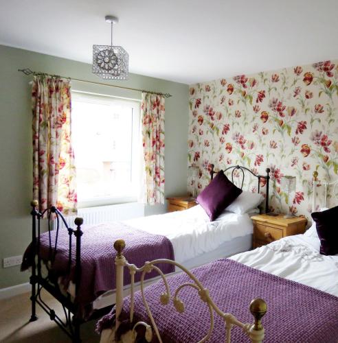 a bedroom with two beds and a window with floral curtains at The Cloisters in York
