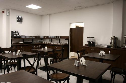 a dining room with tables and chairs and a kitchen at Hotel DOA in Skopje