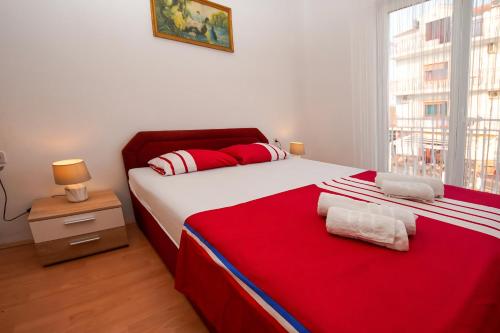 een slaapkamer met een bed met een rode deken en een raam bij Apartment Ajdukovic in Vodice
