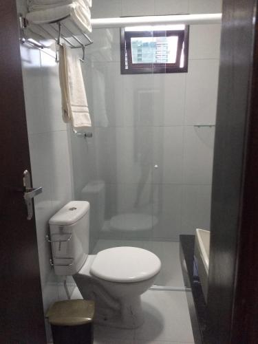 a white bathroom with a toilet and a shower at Pousada Ariús in Campina Grande