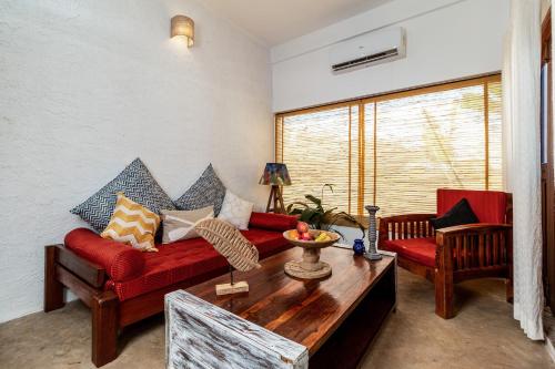 a living room with a red couch and a table at The Hammock Goa in Anjuna