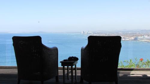 two chairs and a table with a view of the water at Palm Tree Self-Catering Apartment in Gordonʼs Bay