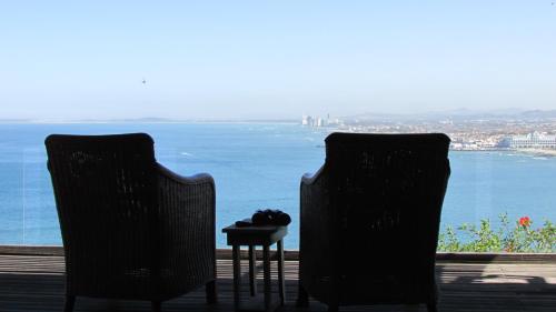 Dos sillas y una mesa con vista al agua. en Palm Tree Self-Catering Apartment, en Gordonʼs Bay