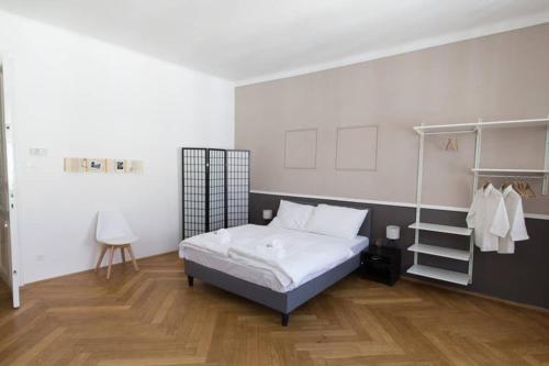 Schlafzimmer mit einem Bett mit weißer Bettwäsche und Holzböden in der Unterkunft Mechthild I levestate in Wien