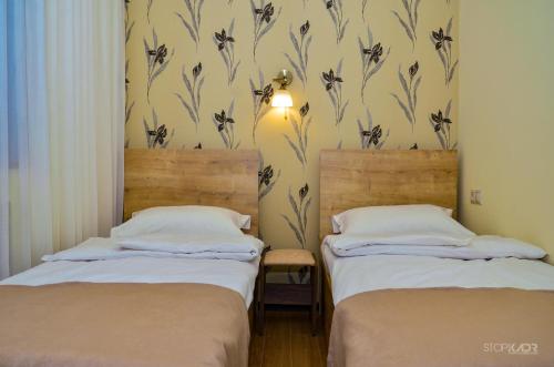 2 Einzelbetten in einem Zimmer mit Tapete in der Unterkunft ASOUR HOTEL in Goris