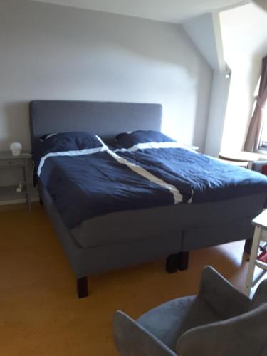 - un lit avec une couette bleue dans une chambre dans l'établissement Meenestee, Borculo, à Borkulo