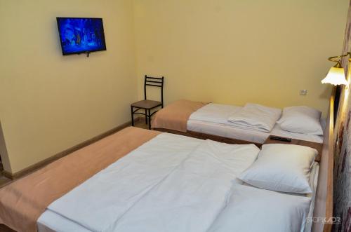 a room with three beds and a tv on the wall at ASOUR HOTEL in Goris